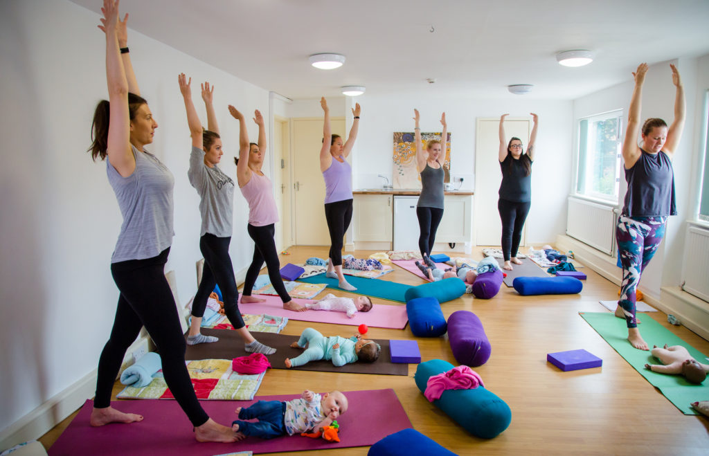 mothers-stood-in-a-yoga-position-on-a-mat-over-their-babies